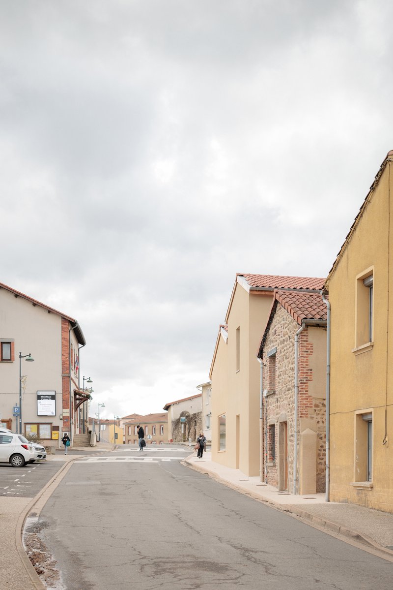 Street view showing mix of new cream-colored plaster and exposed brick facades under overcast sky