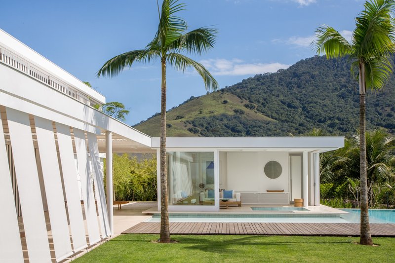 Glass pavilion with recessed lounge overlooking the pool and forested hillside in the distance