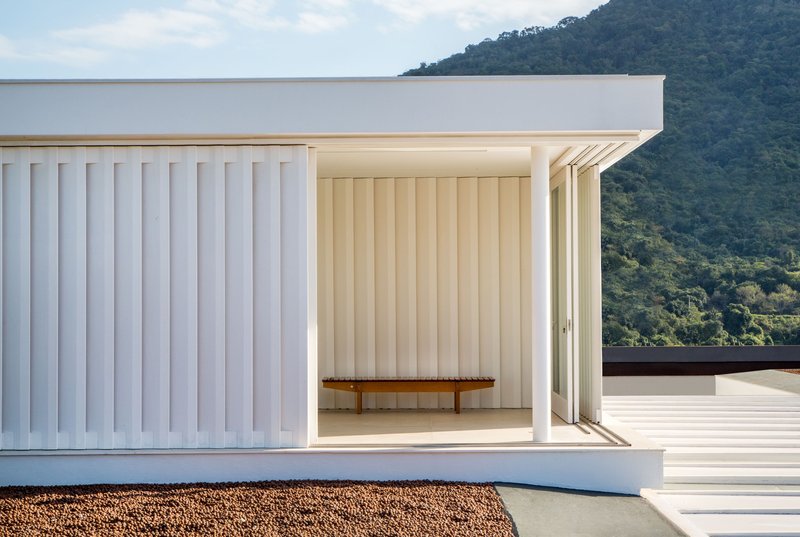Covered terrace with vertical slatted walls opening to a timber bench and hillside beyond