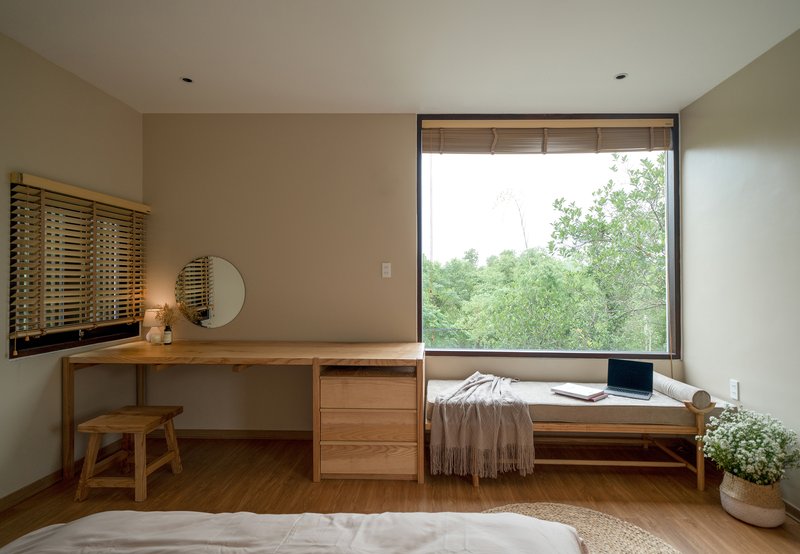 Bedroom with built-in timber desk and window seat overlooking green foliage