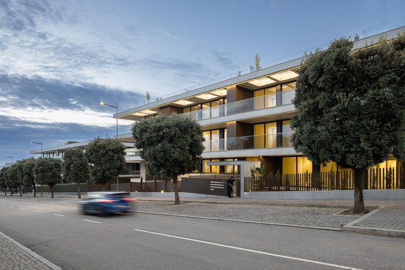 Street elevation at dusk with illuminated interiors and a car passing in motion blur