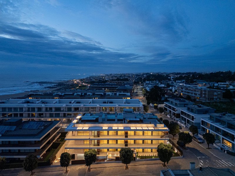 Aerial view of the residential building among neighboring blocks with the coastline visible at dusk