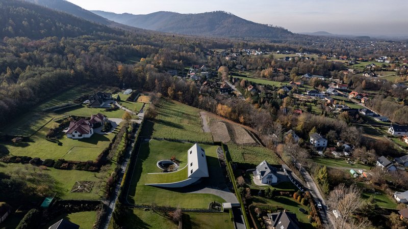 Drone view of the residence set among fields and forested hills at dawn