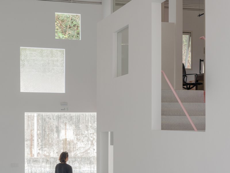 Person standing before three vertically stacked windows with translucent and clear glass overlooking winter trees