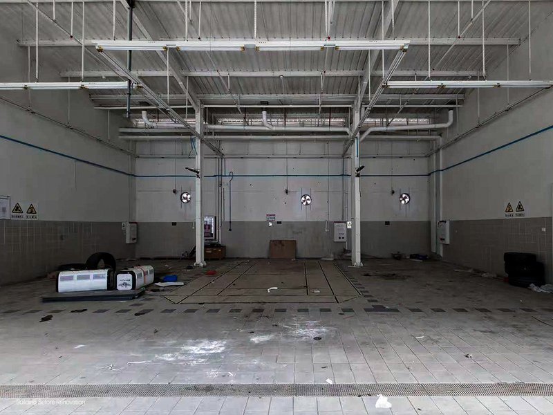 Interior of a garage bay with exposed ceiling ducts and wet concrete floor