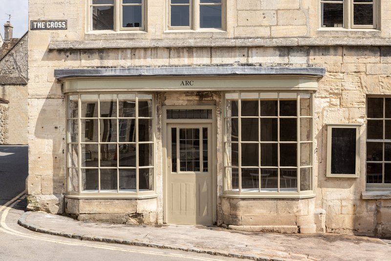 Stone facade with curved bay windows flanking a central doorway beneath zinc coping in daylight