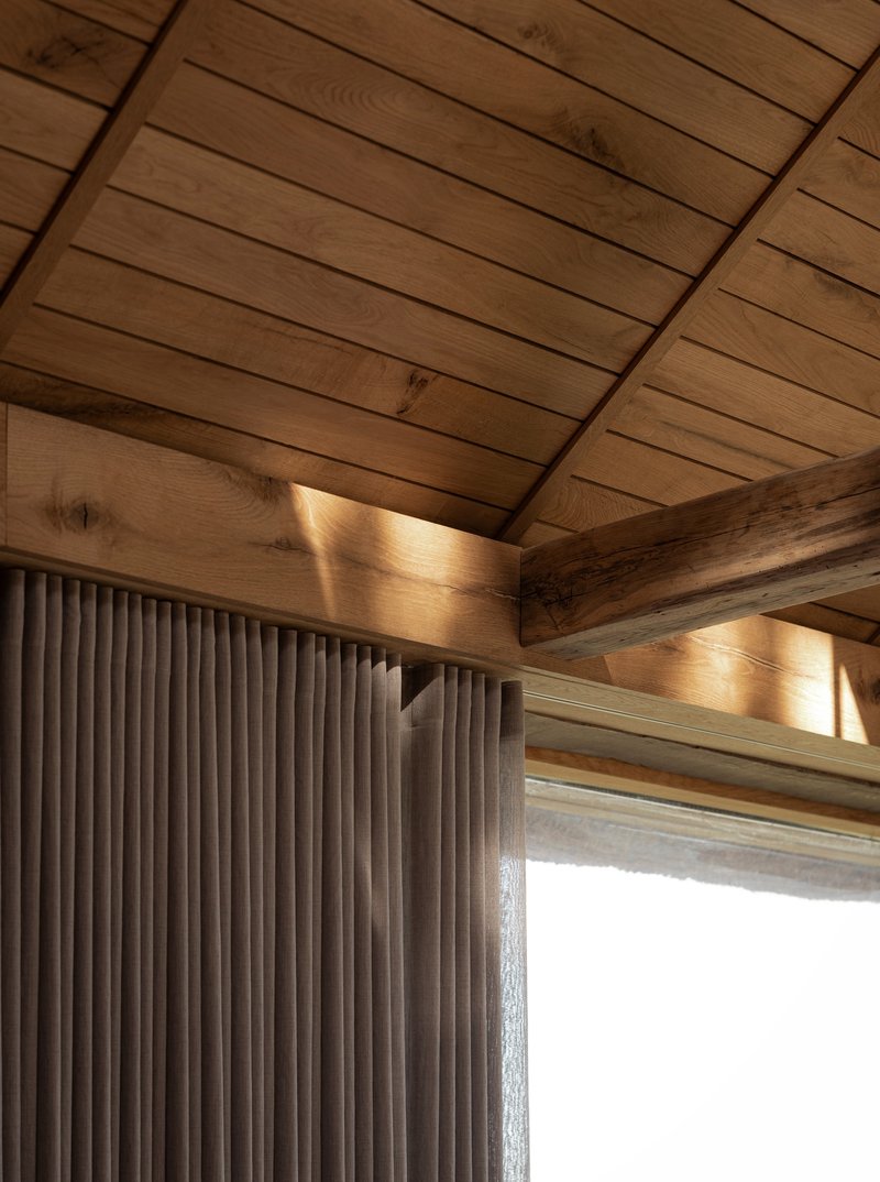 Interior corner showing timber ceiling beams and vertical fluted wall cladding with natural light