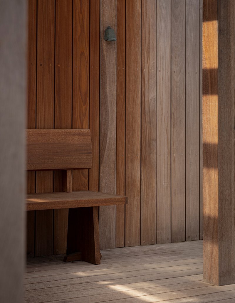 Interior timber wall cladding with a built-in bench illuminated by late afternoon sunlight