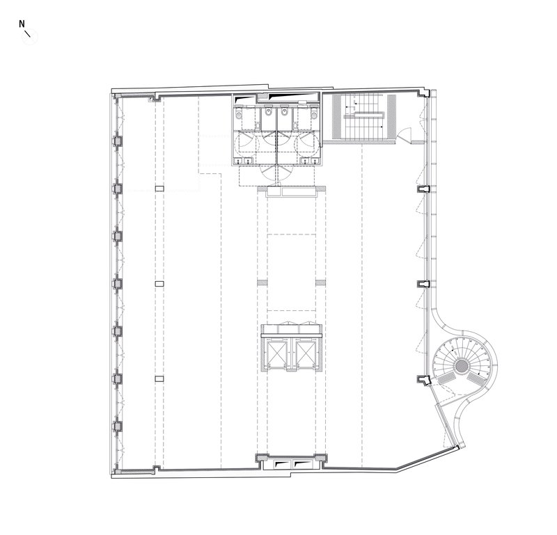 Floor plan drawing showing an open space with central restrooms, stair, and a curved corner staircase