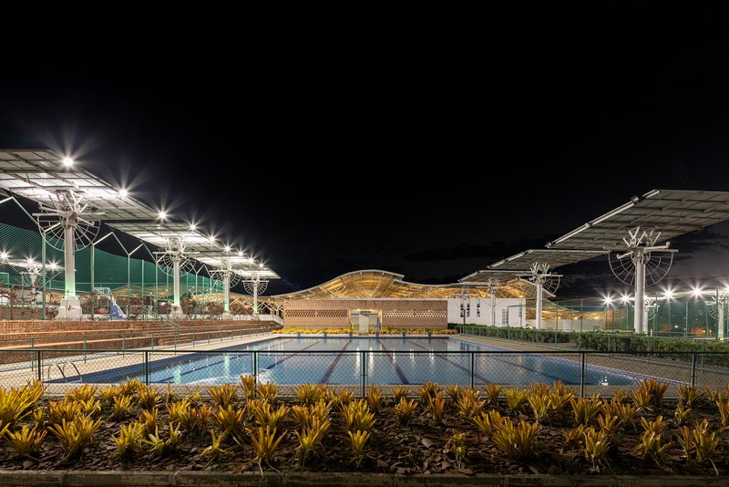 Night view of the reflecting pool with illuminated solar panel canopies and latticed central pavilion
