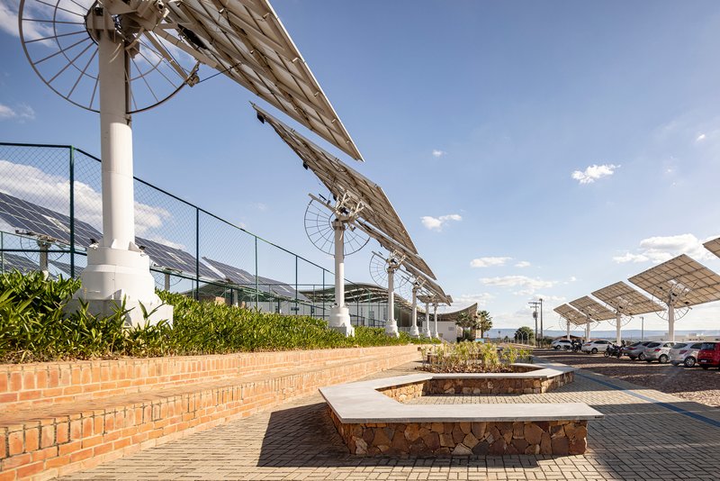 Stone bench beside brick planters and angled solar panel canopy with white support columns