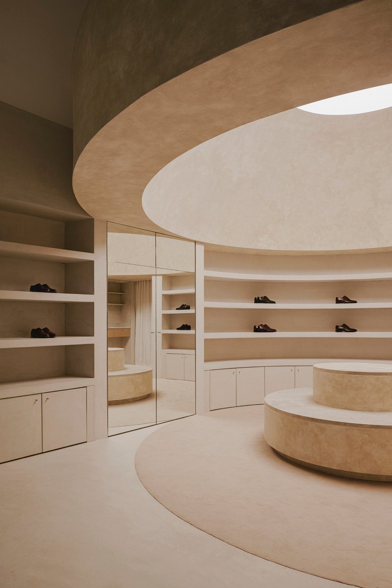 Curved shelving wall with mirror-fronted storage cabinet reflecting the circular display platform