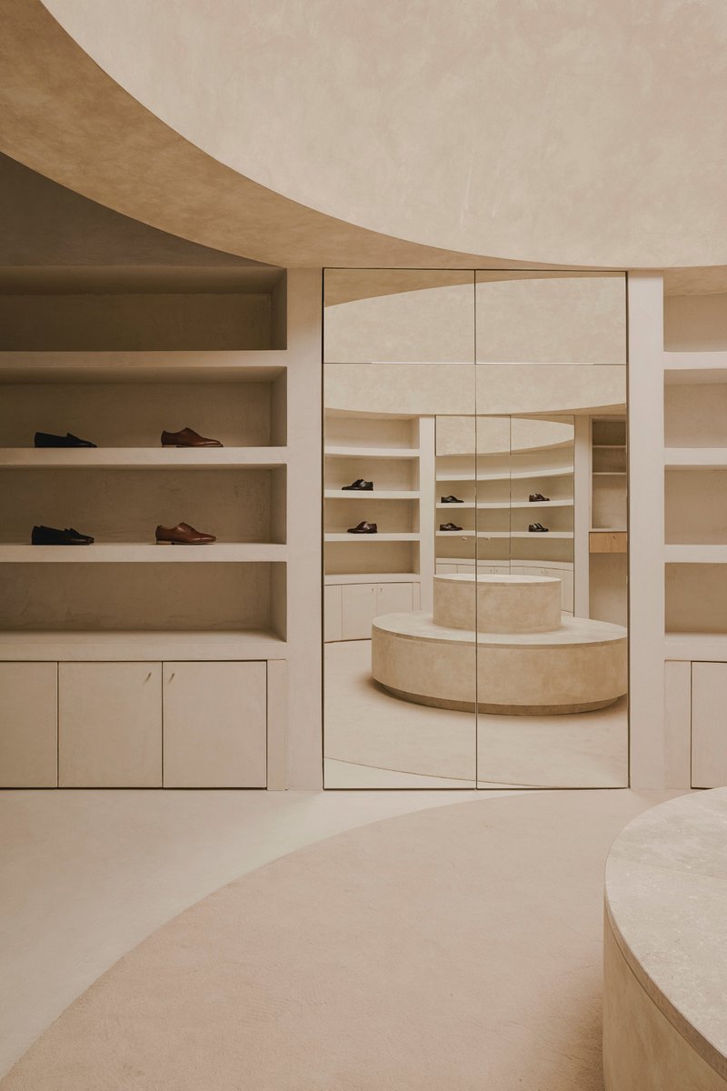 Large mirrored panel reflecting the circular podium and curved display shelves behind