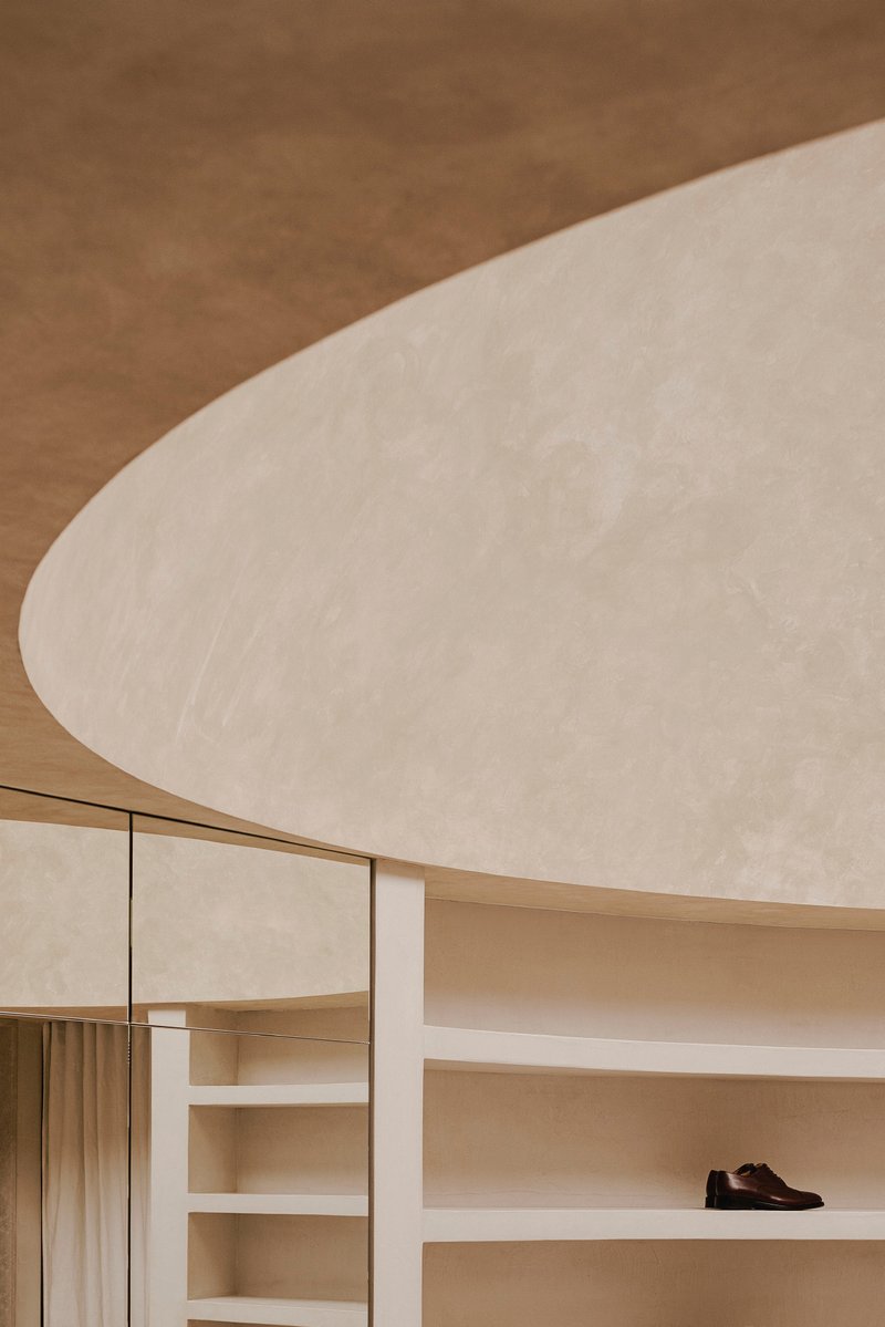 Interior view of pale plaster ceiling vault meeting timber shelving and glass partition
