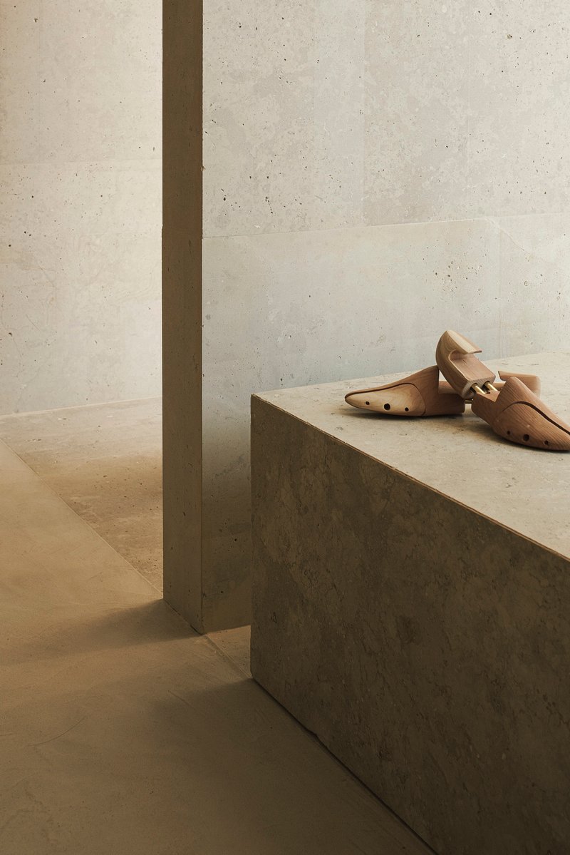 Concrete display plinth beside recessed pilaster against board-formed concrete wall under natural light