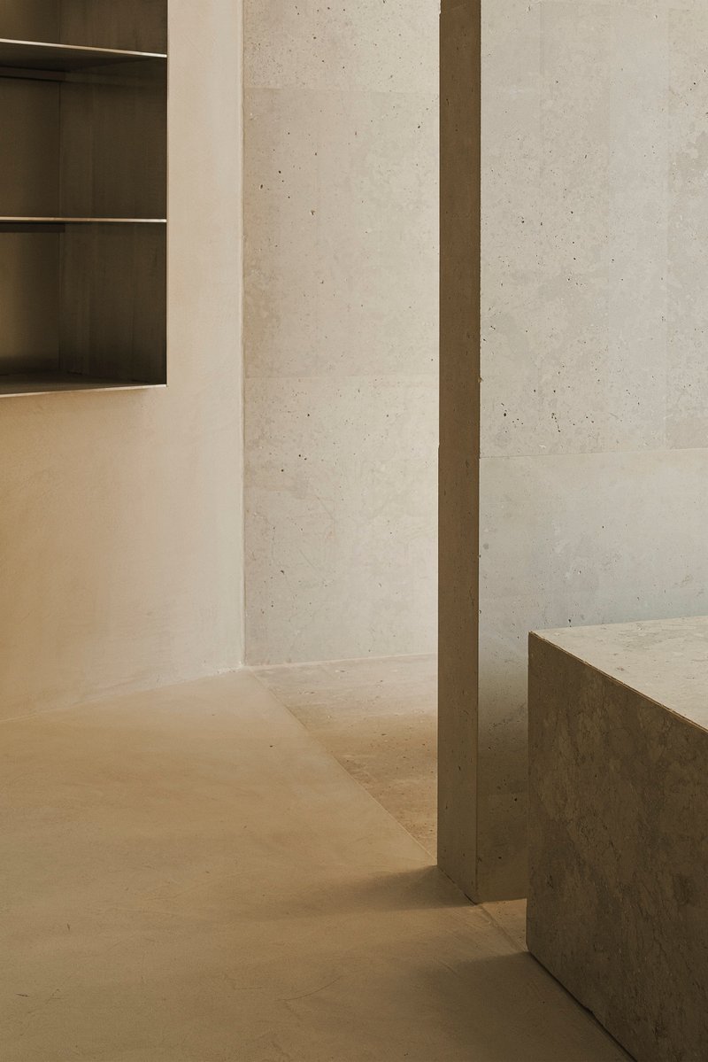 Concrete column and plinth corner beneath board-formed concrete walls and concealed ceiling lighting