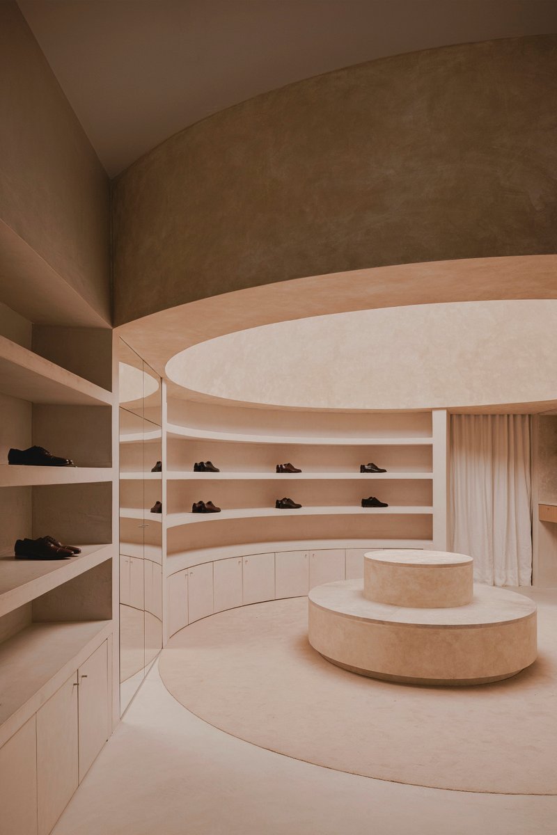 Curved display shelving with shoes set into continuous horizontal niches below layered ceiling bands