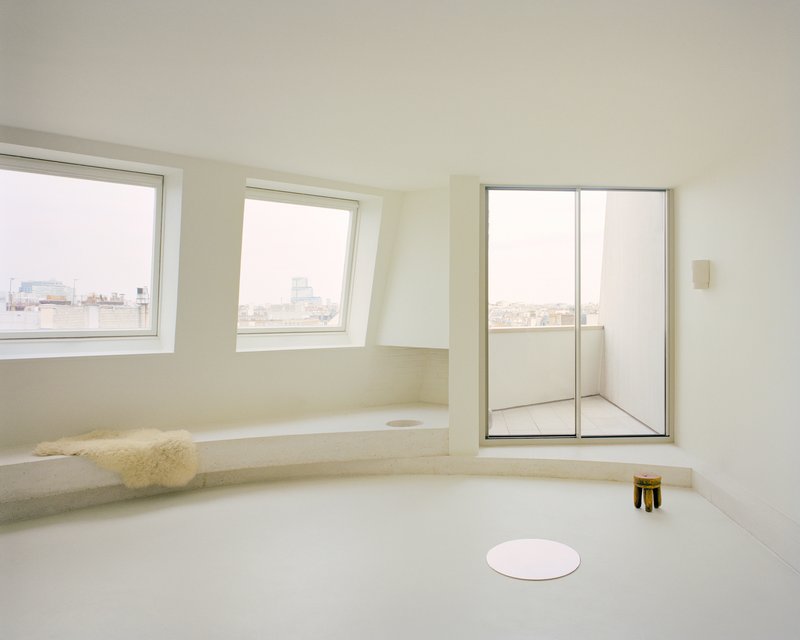 Sunken seating nook with stone bench, sheepskin throw and cityscape windows