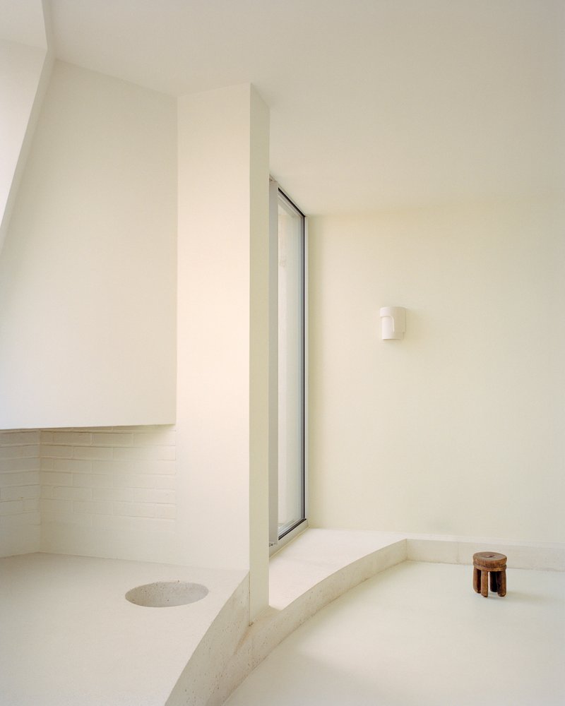 Sunken bathing area with sloped walls and a tall vertical window casting soft light