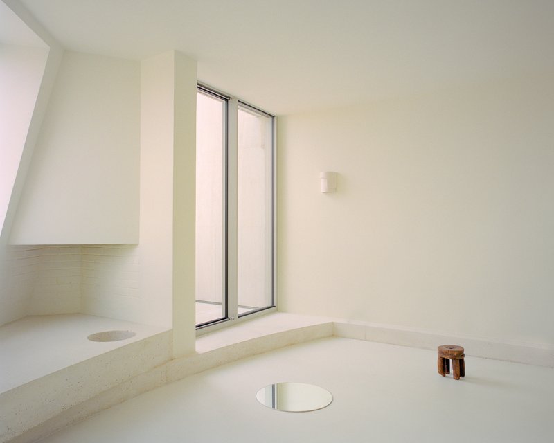 Sunken bath with wide double window and circular floor drain under diffused daylight