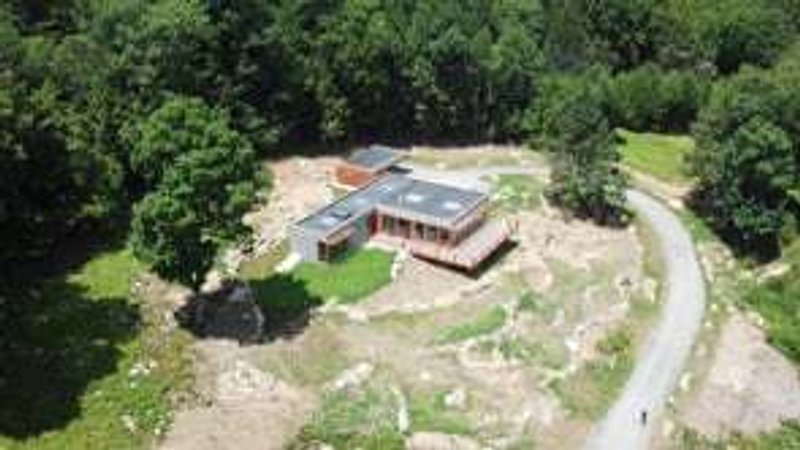Aerial view of the residence on a rocky clearing surrounded by dense forest canopy