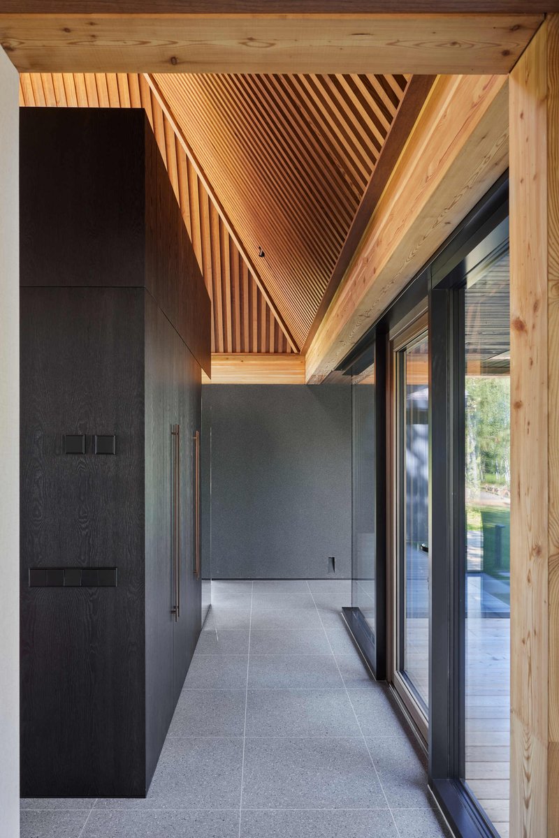 Covered entry corridor with diagonal slatted timber ceiling and dark cabinetry along one wall