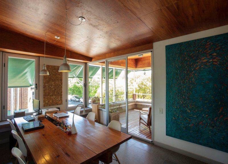 Dining area with angled timber ceiling and sliding glass doors to exterior terrace under bright daylight