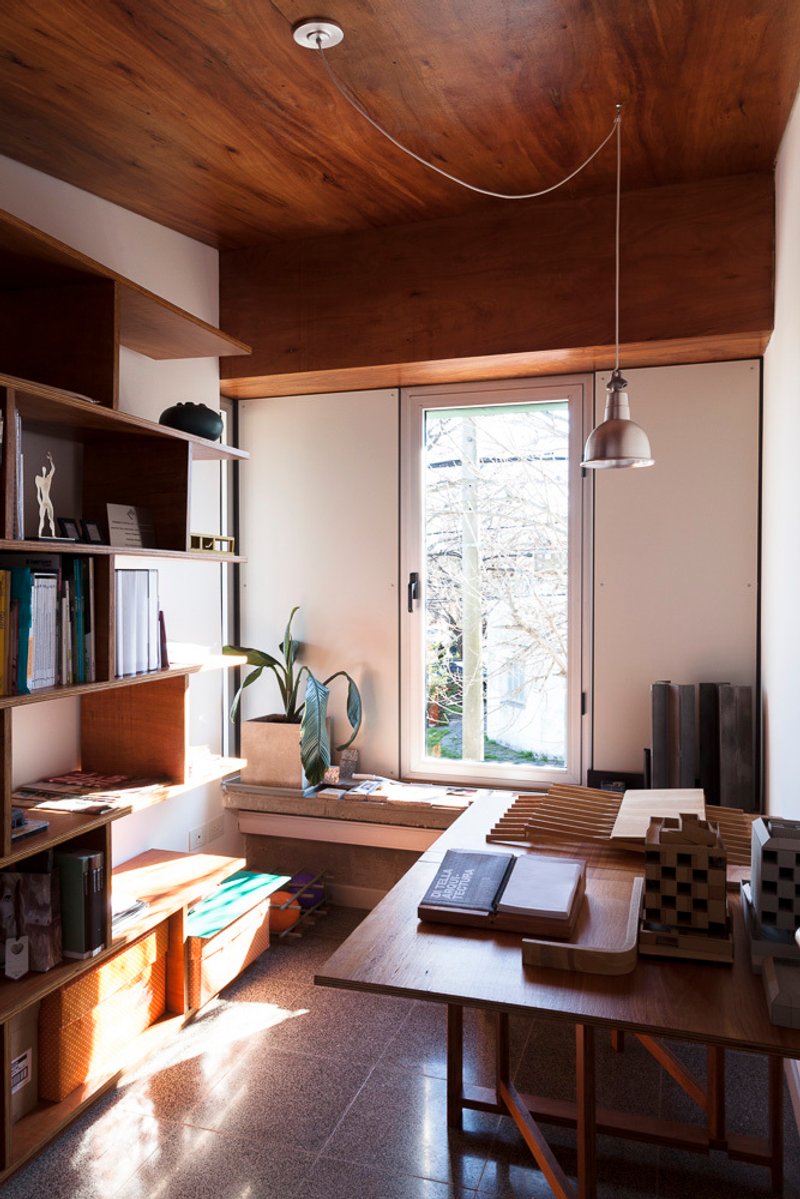 Work desk beneath glazed door with afternoon sun casting shadows across terrazzo floor