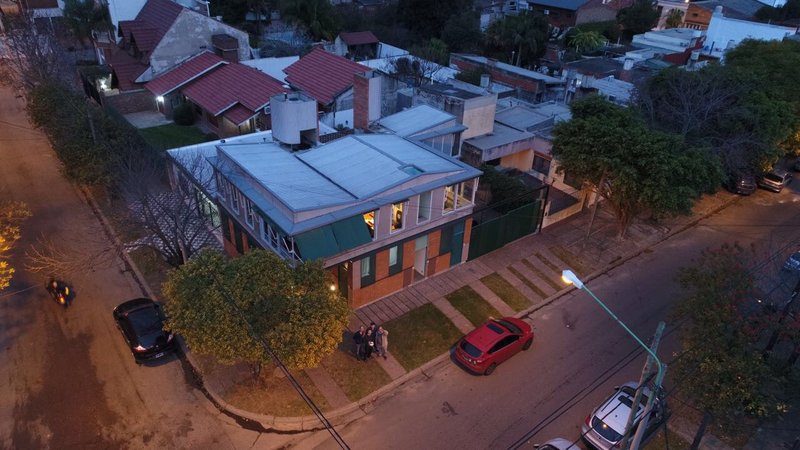 Aerial view of corner residence with corrugated metal roof and brick facade at dusk