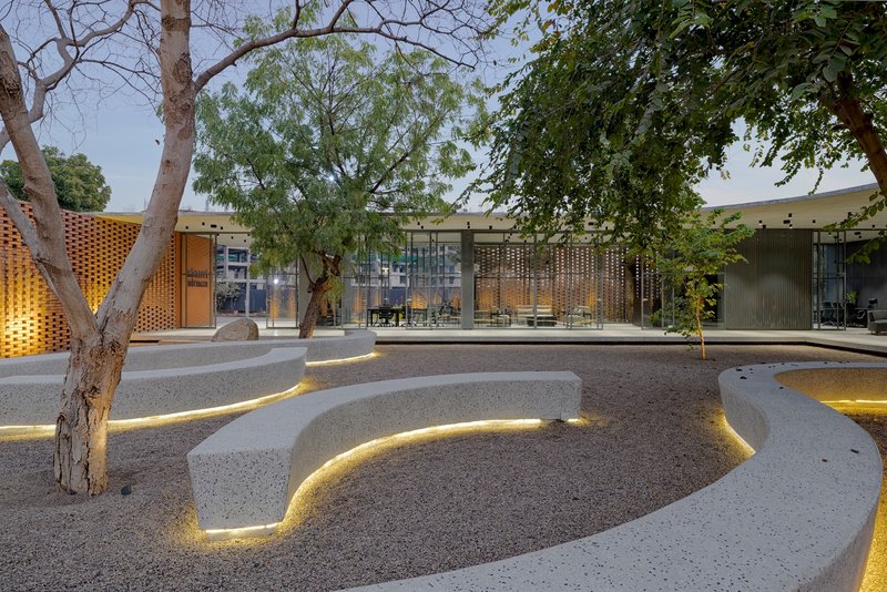 Terraced gravel seating area with integrated strip lighting at dusk beneath mature trees