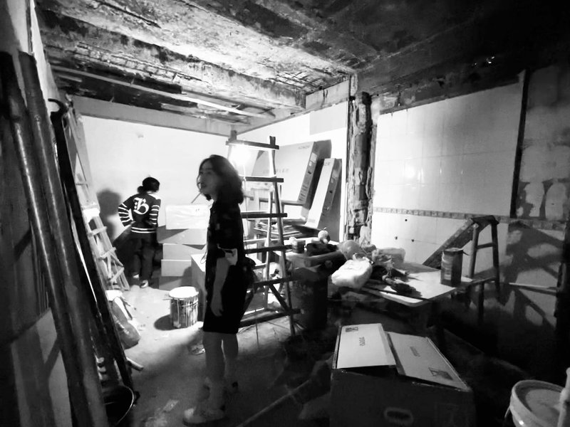 Interior renovation space with exposed timber ceiling beams and workers amid construction materials