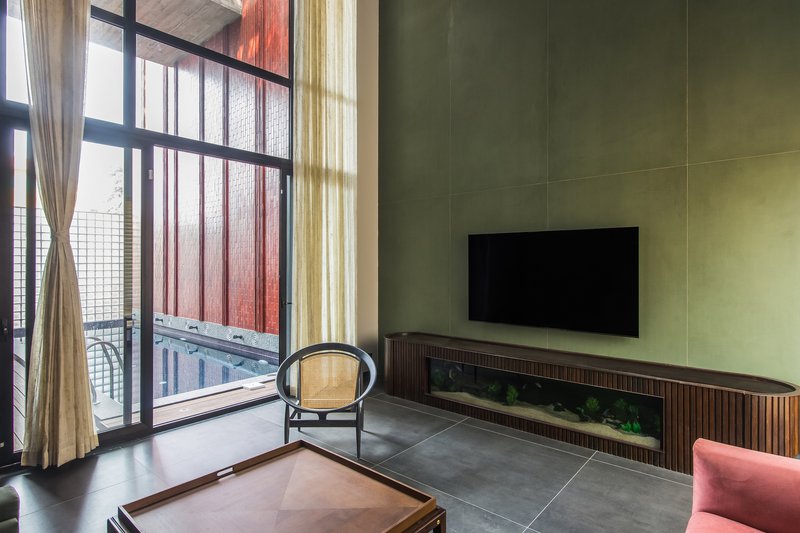 Living room with yellow paneled wall and glass-block balcony doors filtered by pink and beige curtains