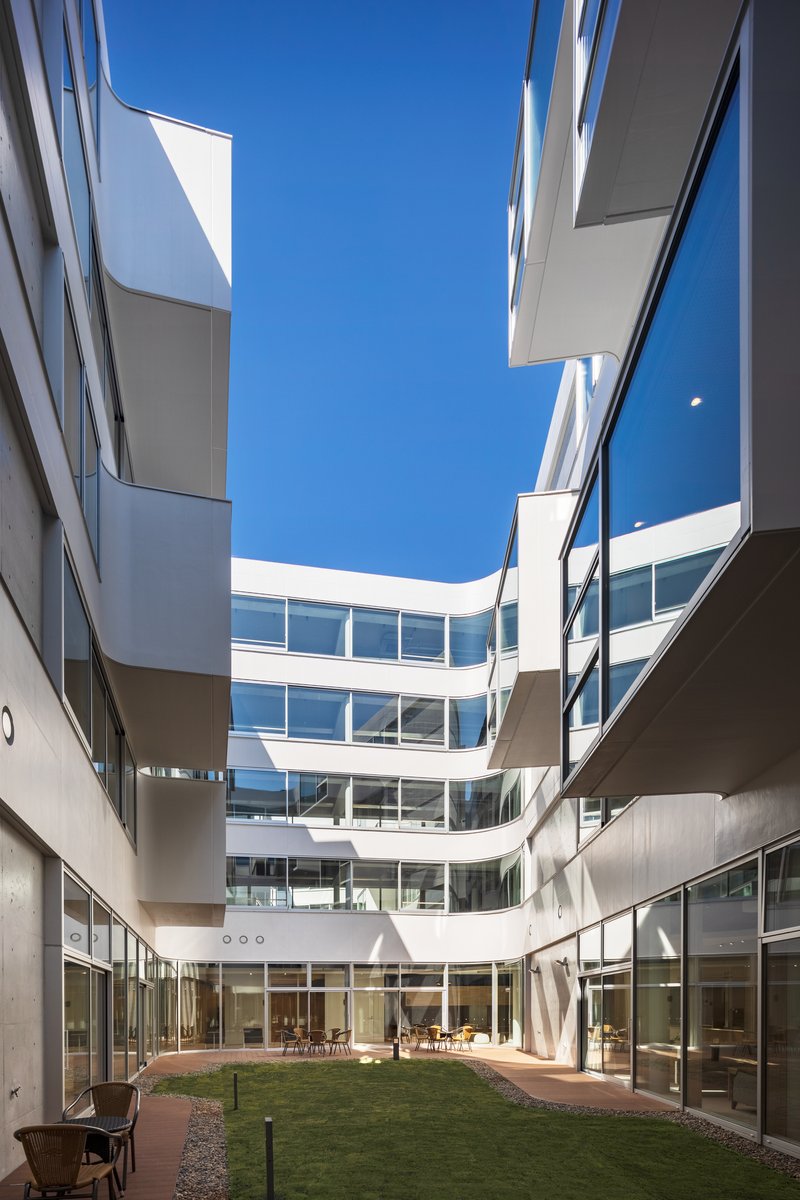 Upward view of the courtyard showing curved balconies framing a ribbon of blue sky