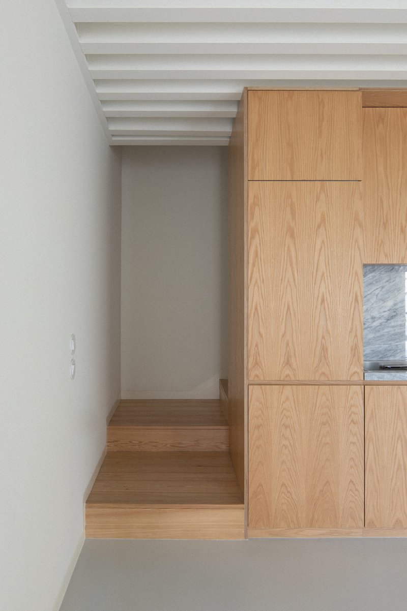 Oak built-in seating nook with storage panels beneath exposed white painted ceiling joists