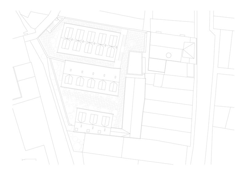Site plan drawing showing three rows of pitched-roof townhouses on an angled lot with surrounding streets