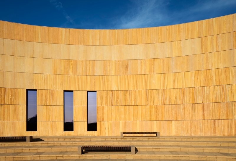 Close view of the curved sandstone facade with three tall narrow windows and stepped terrace below
