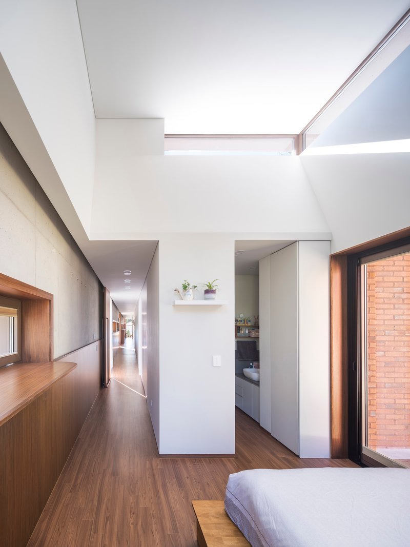 Open bedroom plan with clerestory slot and corridor leading past concrete walls to adjacent spaces