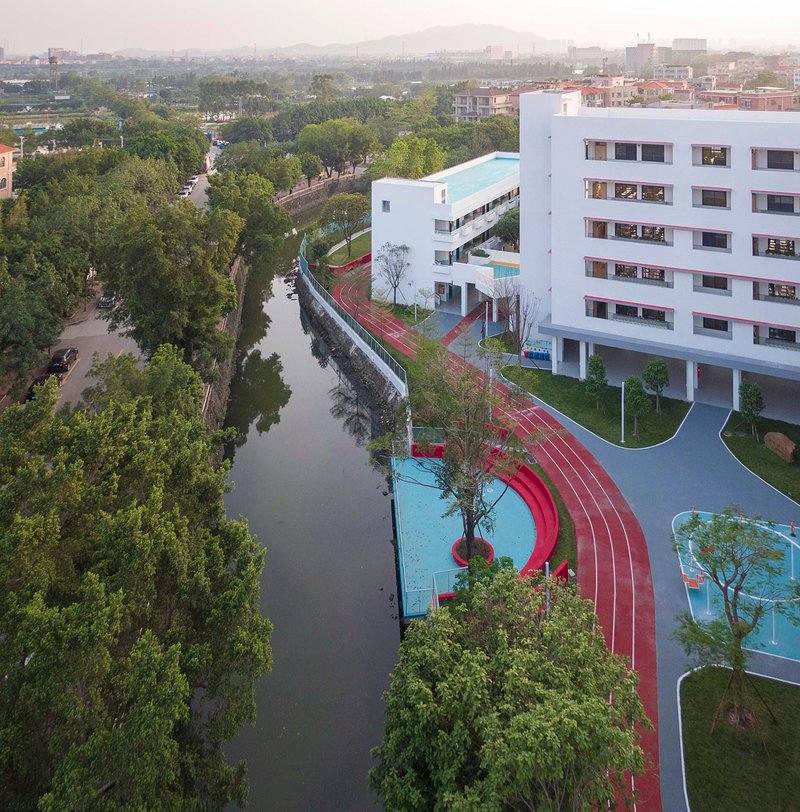 Aerial view of the red running track curving along the canal with white classroom block at dusk