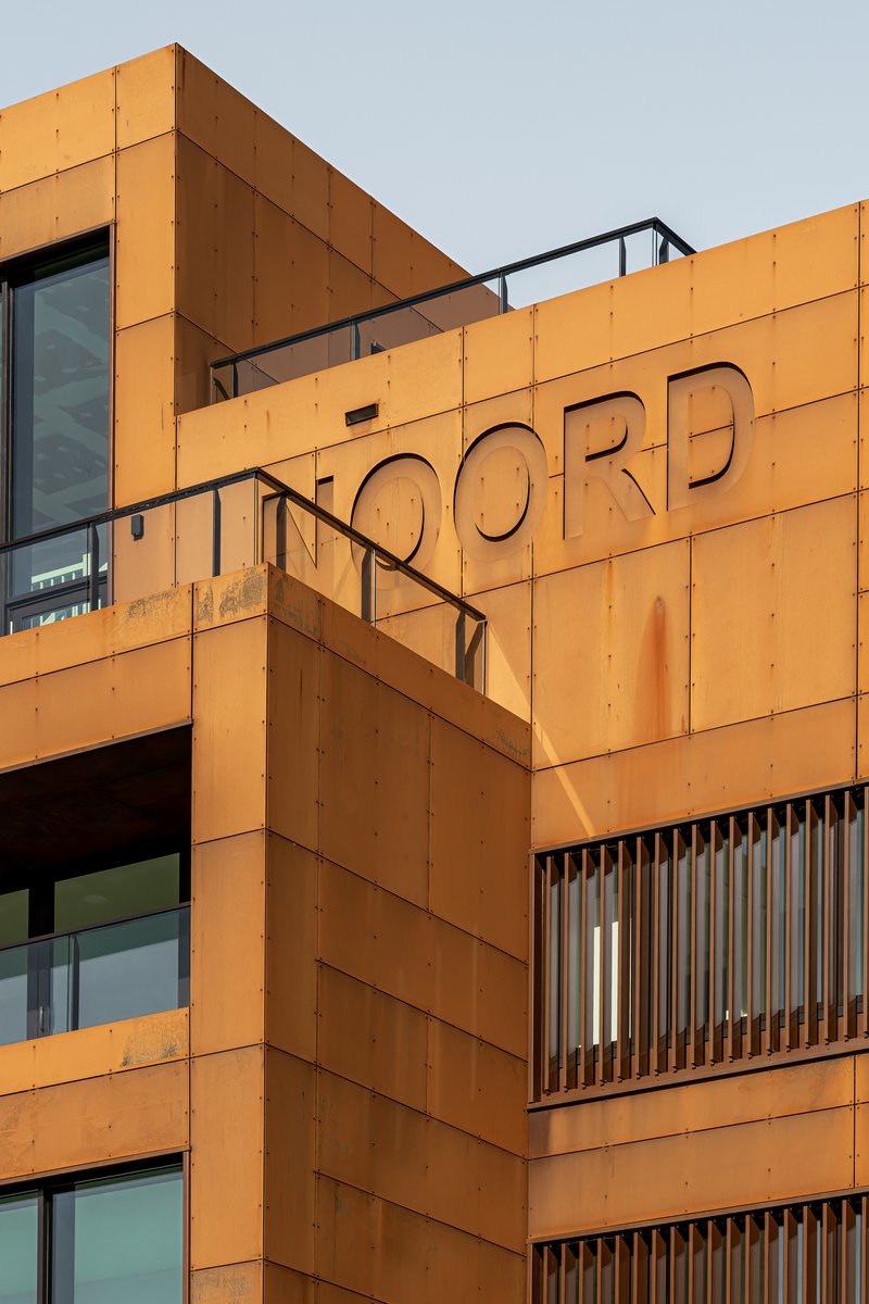 Orange paneled facade with recessed lettering and vertical slat screening at upper levels