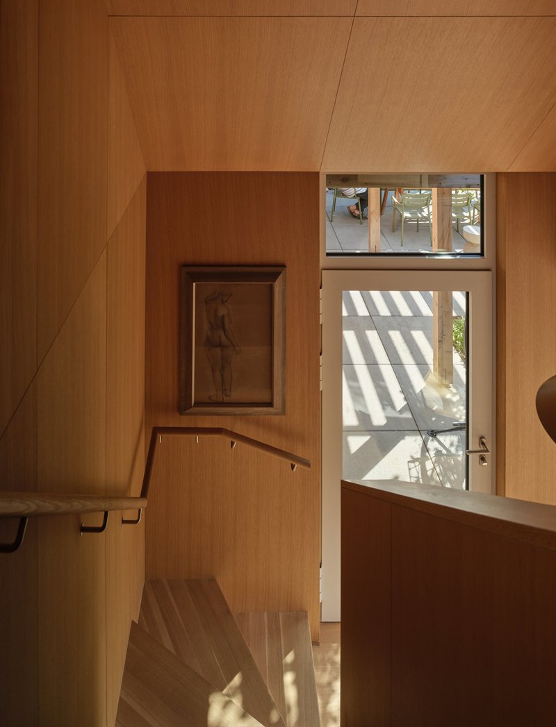 Stairwell with wood treads and clerestory windows casting striped shadows on the landing