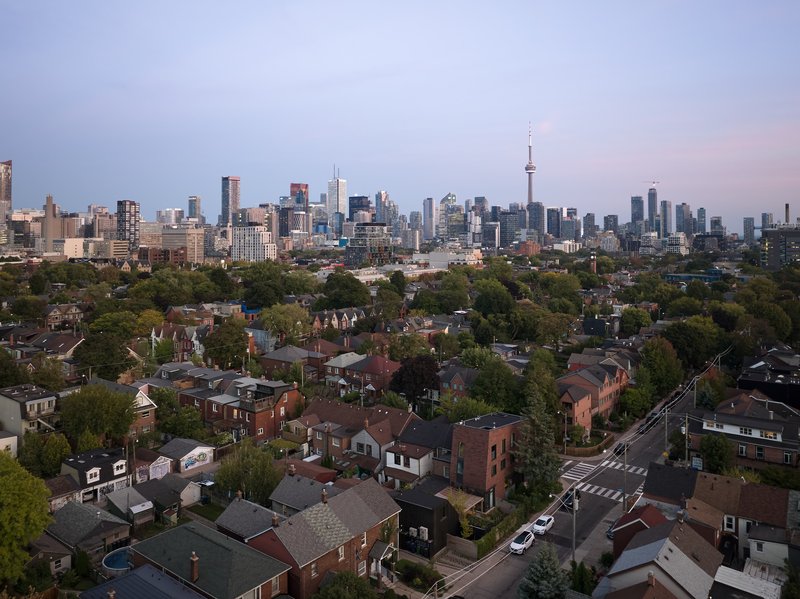 Aerial view of residential neighborhood with skyline towers visible under pink evening sky