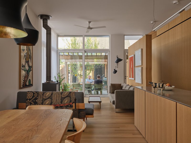 Open plan living space with wood-burning stove, timber millwork, and glazed doors to rear courtyard
