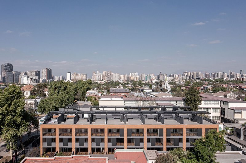 Elevated view of the brick and dark metal facade with rooftop solar panels against the distant skyline