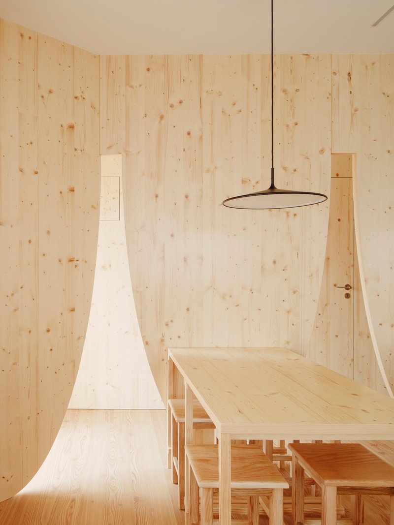 Light wood dining area with tapered chimney form and circular pendant light fixture above