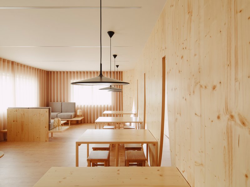 Open living and dining space with timber slat curtain wall filtering daylight