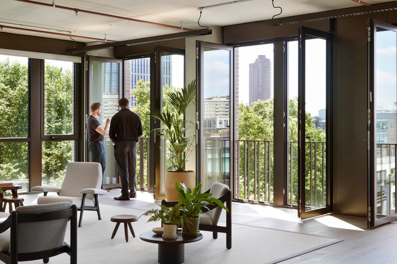 Full-height folding glass doors opening onto a balcony with two residents and potted plants