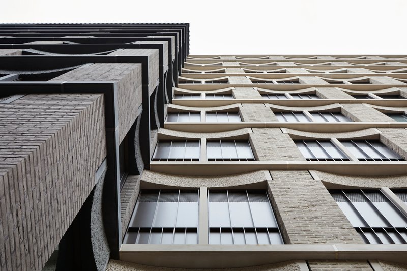 Upward view contrasting a dark stepped corner against curved concrete balcony parapets