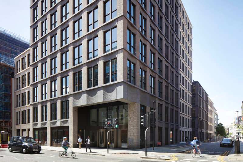 Corner entrance with cyclists and pedestrians passing on a sunny afternoon