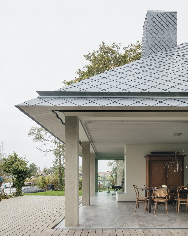 Detail of the overhanging roof eave with diamond-pattern zinc shingles above concrete columns