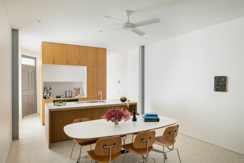 Open dining area with oak island kitchen and white oval table beneath ceiling fan